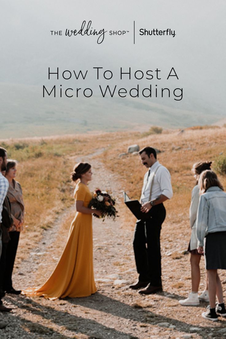 a couple getting married in the middle of a field with other people standing around and looking at each other