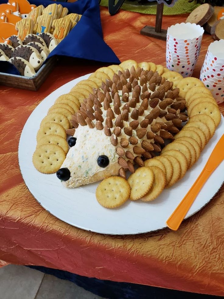 a hedgehog made out of crackers sitting on a plate next to some snacks