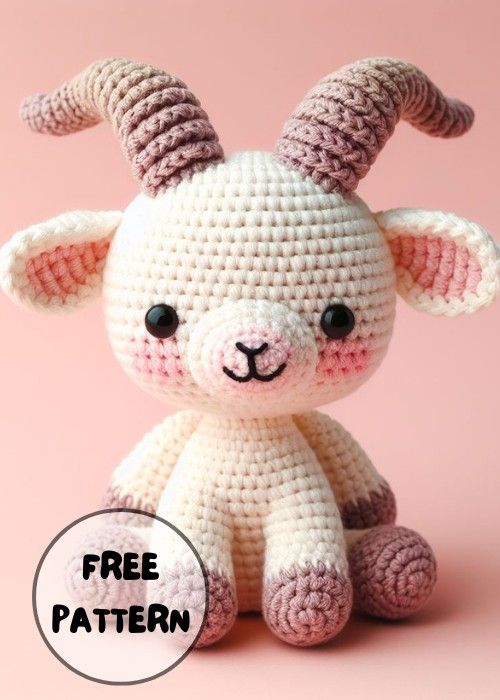 a crocheted stuffed animal with horns on it's head, sitting in front of a pink background