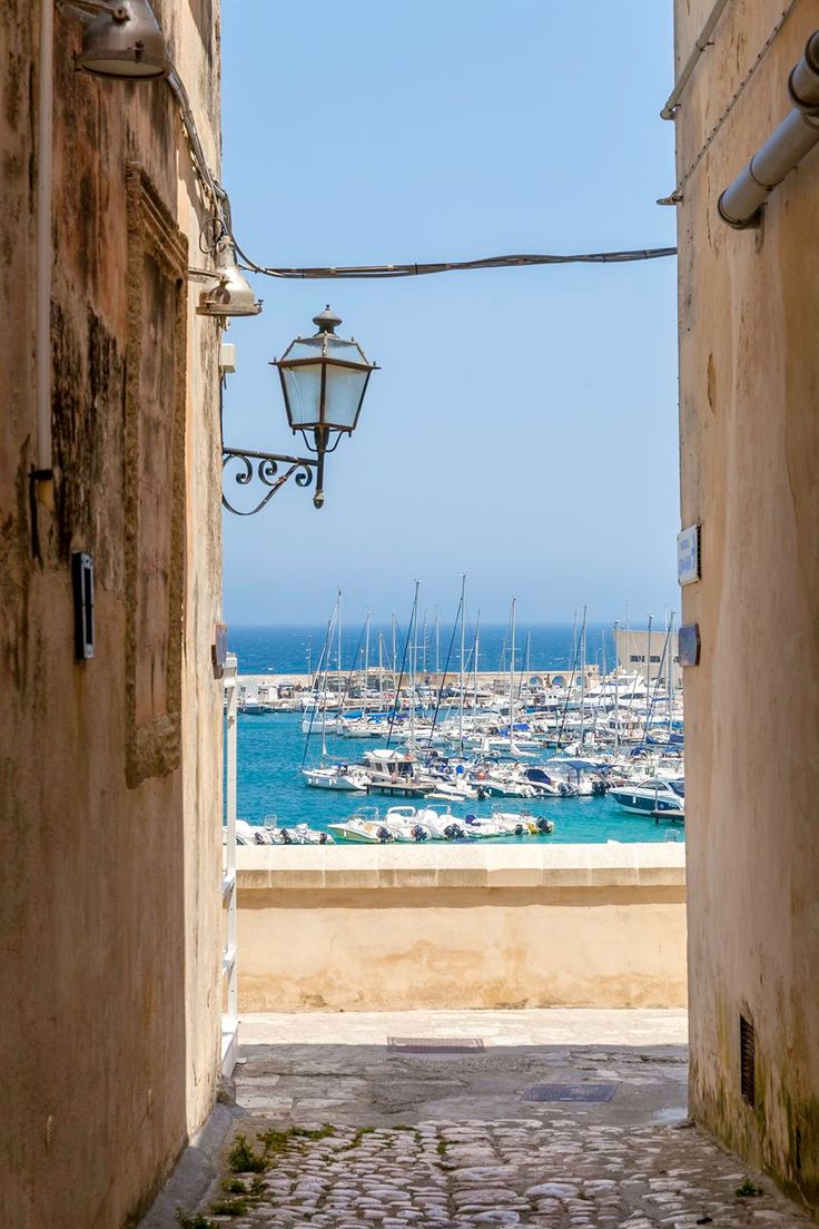 an alley way leading to the beach with boats in the water and buildings on either side