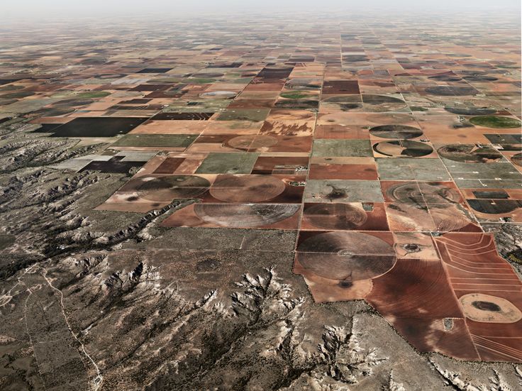 an aerial view of a large field with many different patches of grass and trees in it