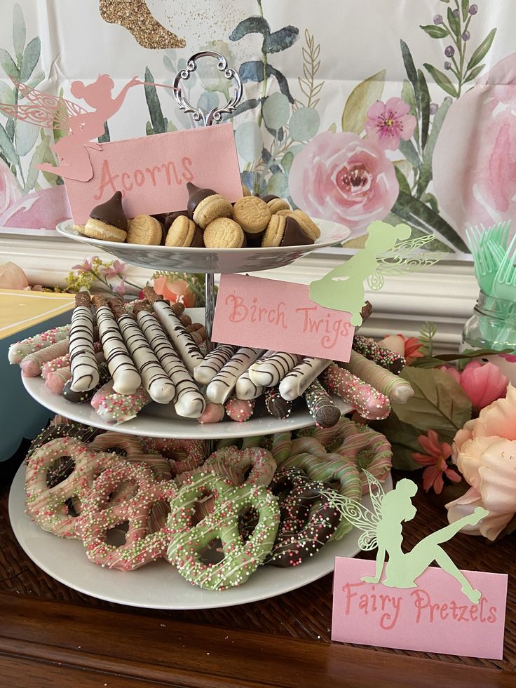 a table topped with three tiered trays filled with donuts and pretzels