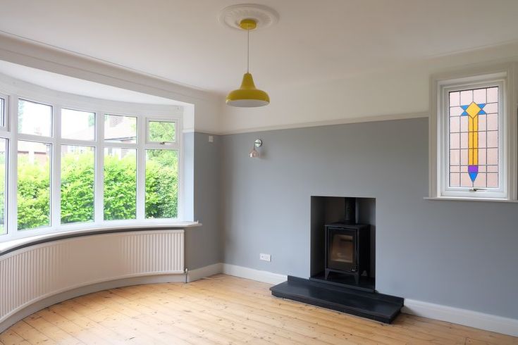 an empty room with a wood burning stove in the corner and two windows on either side