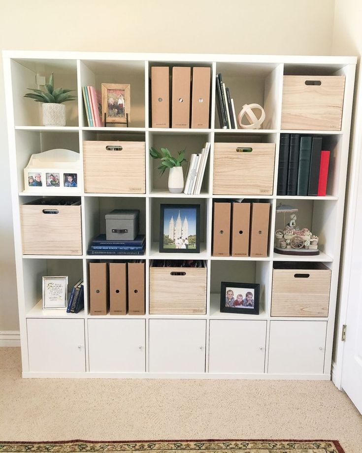 a white bookcase filled with lots of books next to a rug on the floor