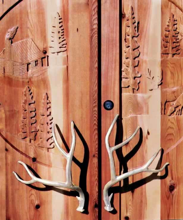 two deer antlers are mounted to the side of a wooden door with writing on it