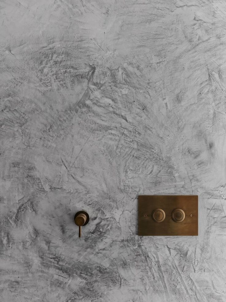 a wall mounted faucet on the side of a white and gray marbled wall