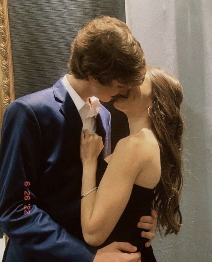 a man and woman are kissing in front of a mirror with their arms around each other