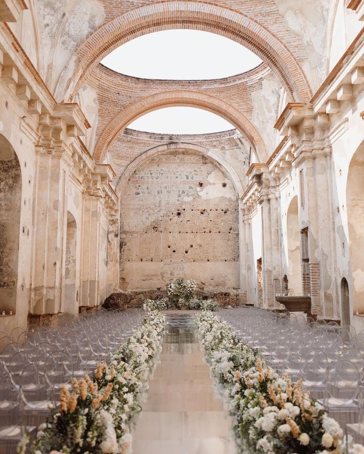 an empty church with rows of pews and flowers on the aisle in front of it