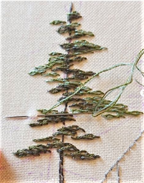 the needle is being used to sew a small pine tree with green needles on it