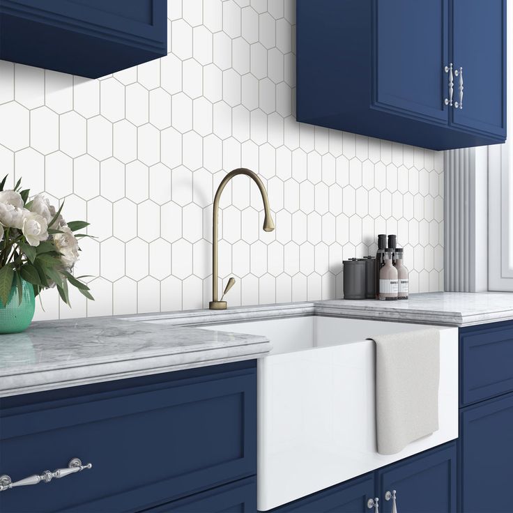 a kitchen with blue cabinets and marble counter tops, white tiles on the backsplash