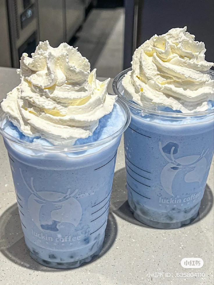 two cups filled with whipped cream on top of a table