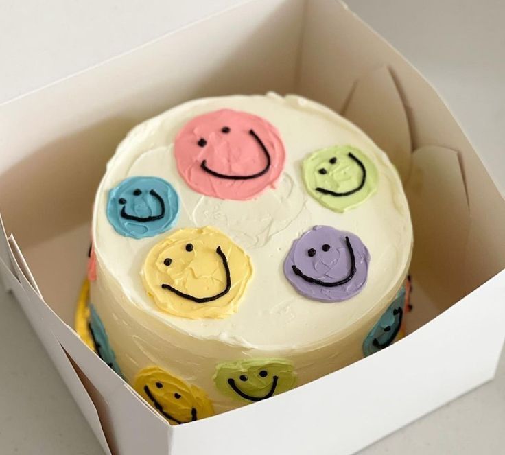 a white cake in a box with smiley faces on it