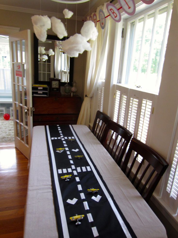 a dining room table is decorated with paper airplanes and streamers that are hanging from the ceiling