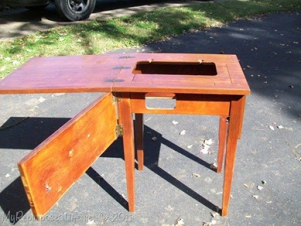 a wooden desk sitting on the side of a road next to a parked car in front of a house