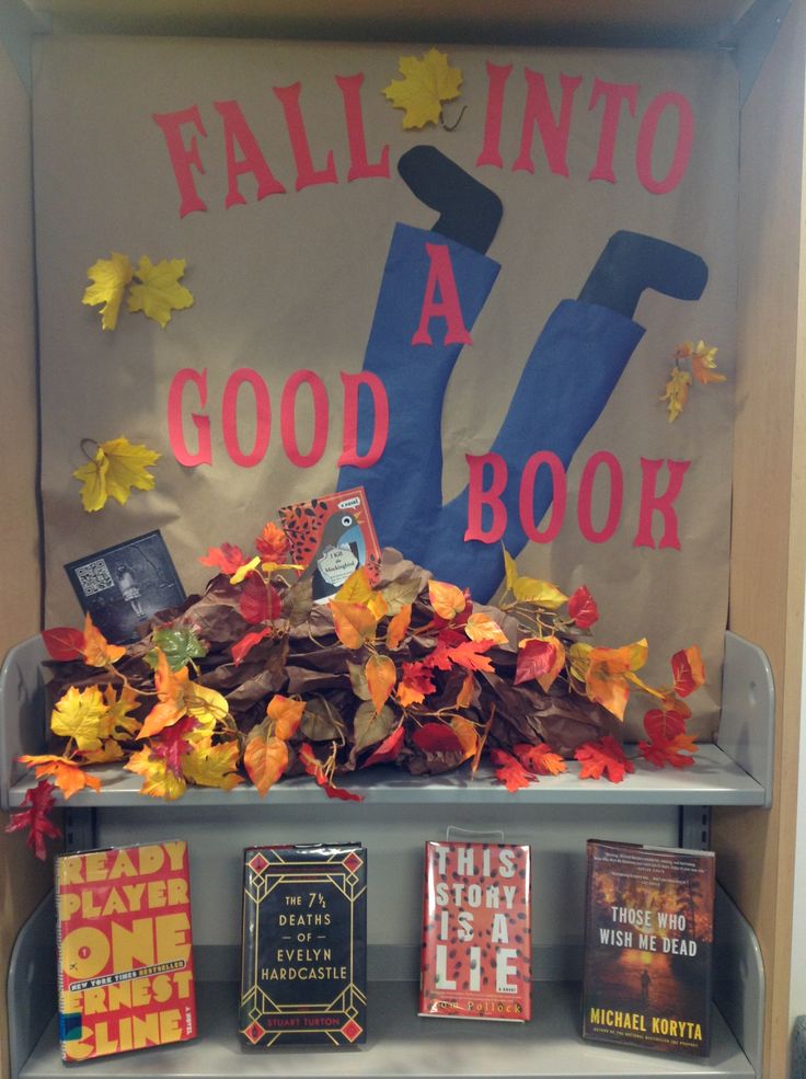 the fall into a good book display with books on it and leaves all over the shelf