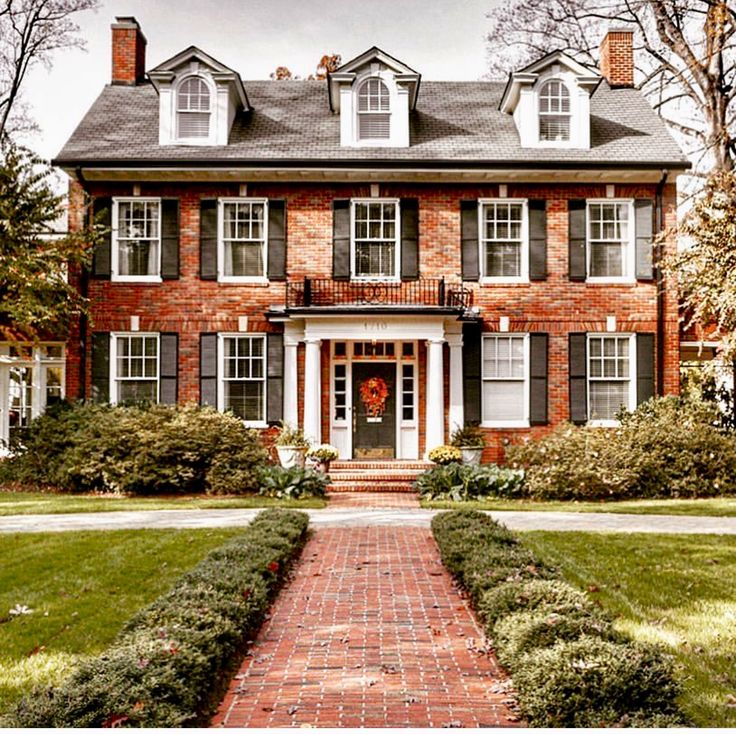 a large brick house with white trim and black shutters on the front door is shown