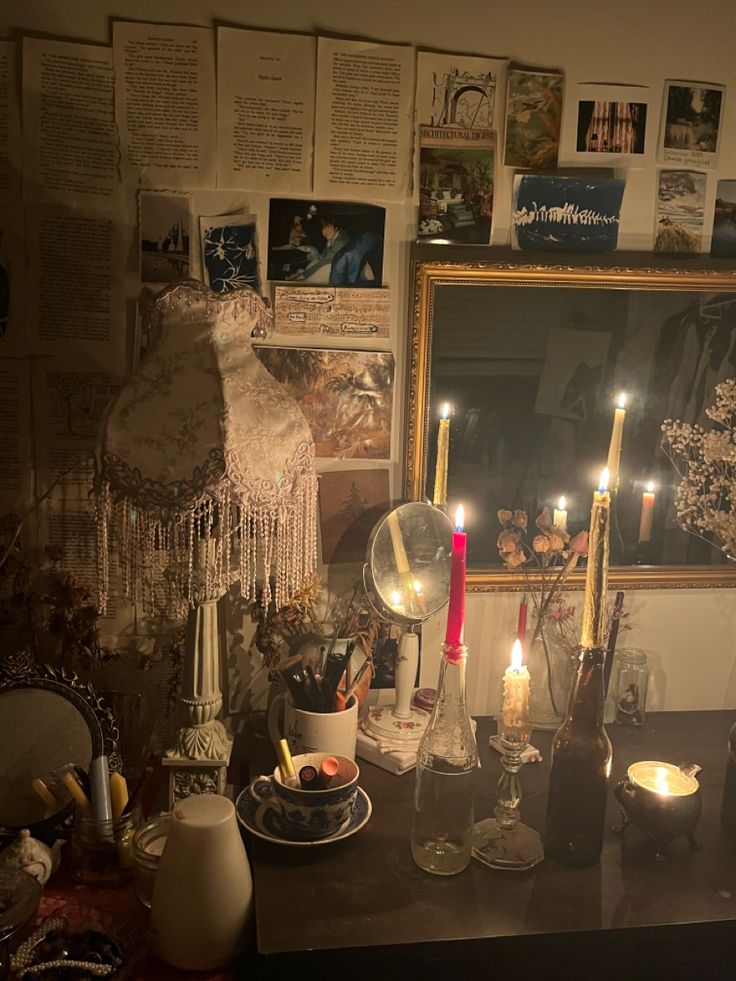 candles are lit on a table in front of a mirror with pictures and other items