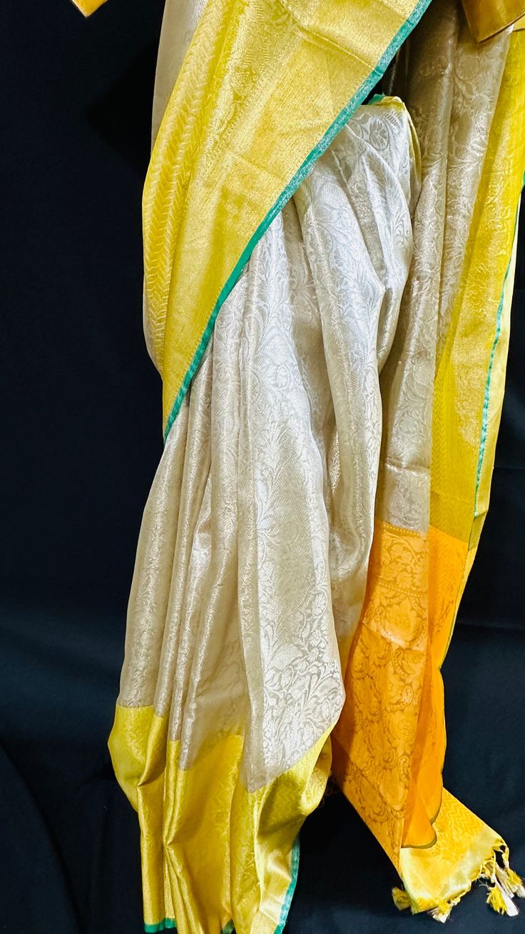 Bringing you the finest collection of Banarasi Tissue Silk Sarees yet another stylish , elegant and timeless piece from our master weavers in Banaras. Adorn this Kanchipuram inspired tissue silk saree in gold zari with floral jaal all over. With double border on the bottom and contrast color pallu this piece is gorgeous to the core and timeless . Luxurious fabric with softness and sheen just remarkable. Photos don't do justice .. this saree is just... glamorous Comes with fall/ Pico / tassels and a stitched blouse. Blouse Detail: Stitched blouse size 38, upto 42. front closure and padded with elbow level sleeves. Saree comes in a beautiful saree cotton bag. Note: Colors that show up on your screen may vary slightly from the actual product due to variations in settings. Also, the actual pro Gold Handloom Pre-draped Saree For Wedding, Elegant Yellow Pre-draped Saree With Zari Weaving, Transitional Gold Banarasi Silk Pre-draped Saree, Gold Anarkali Banarasi Silk Pre-draped Saree, Gold Silk Pre-draped Saree For Eid, Traditional Gold Pre-draped Saree With Self Design, Semi-stitched Gold Banarasi Silk Traditional Wear, Gold Katan Silk Pre-draped Saree With Pallu, Yellow Handloom Pre-draped Saree For Wedding