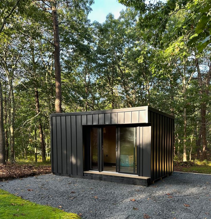 a small black building sitting in the middle of a forest