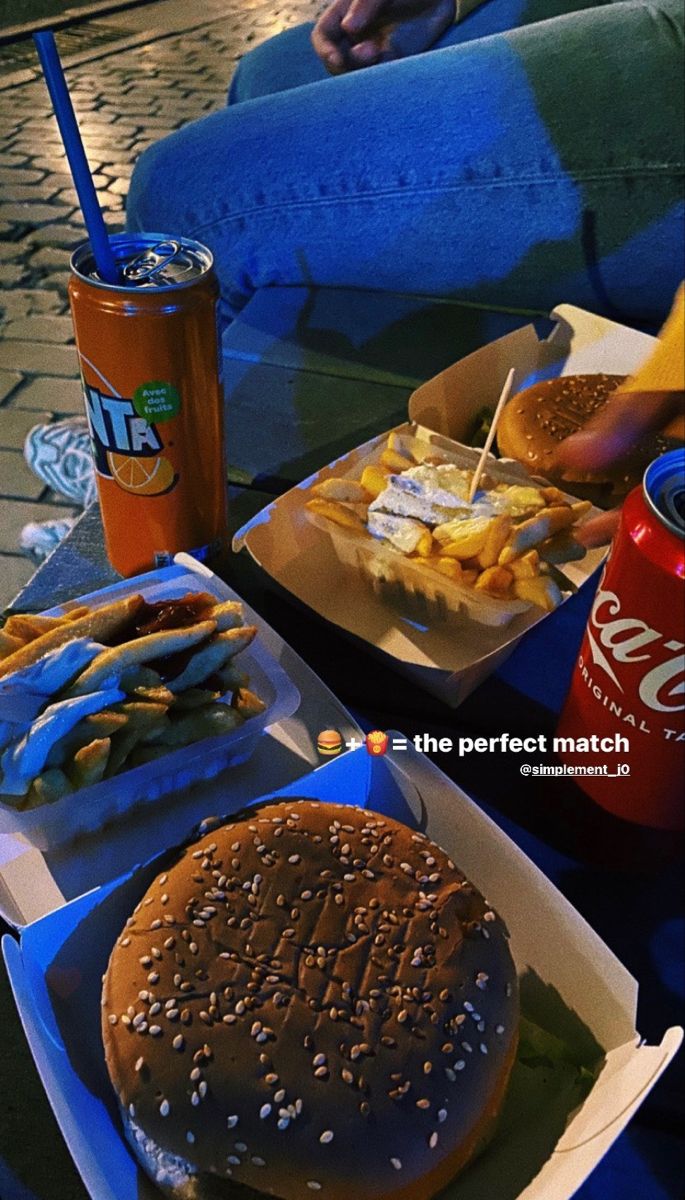 there is a hamburger, fries and soda on the table with people sitting around it