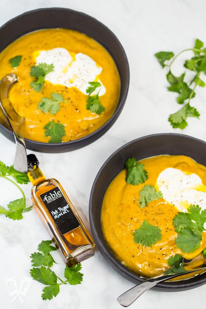 two bowls filled with pumpkin soup and topped with cilantro