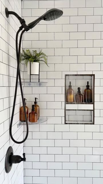 a bathroom with white subway walls and black faucet shower head, soap dispensers on the wall