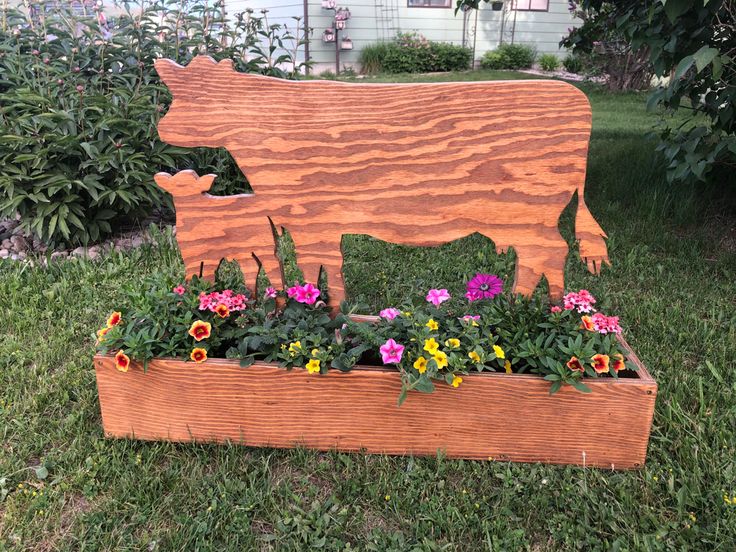 a wooden cow planter with flowers in it