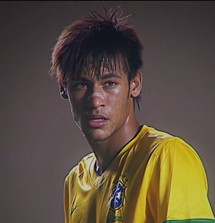 a young man in a yellow soccer uniform looking at the camera