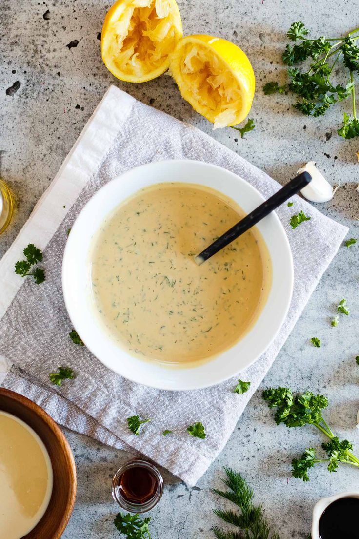 a bowl of soup on top of a table next to some lemons and parsley