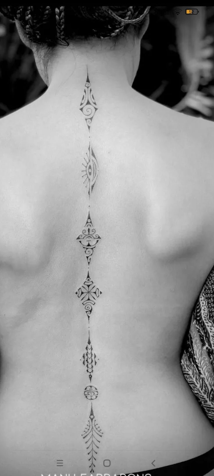 the back of a woman's neck with an intricate design on her lower back