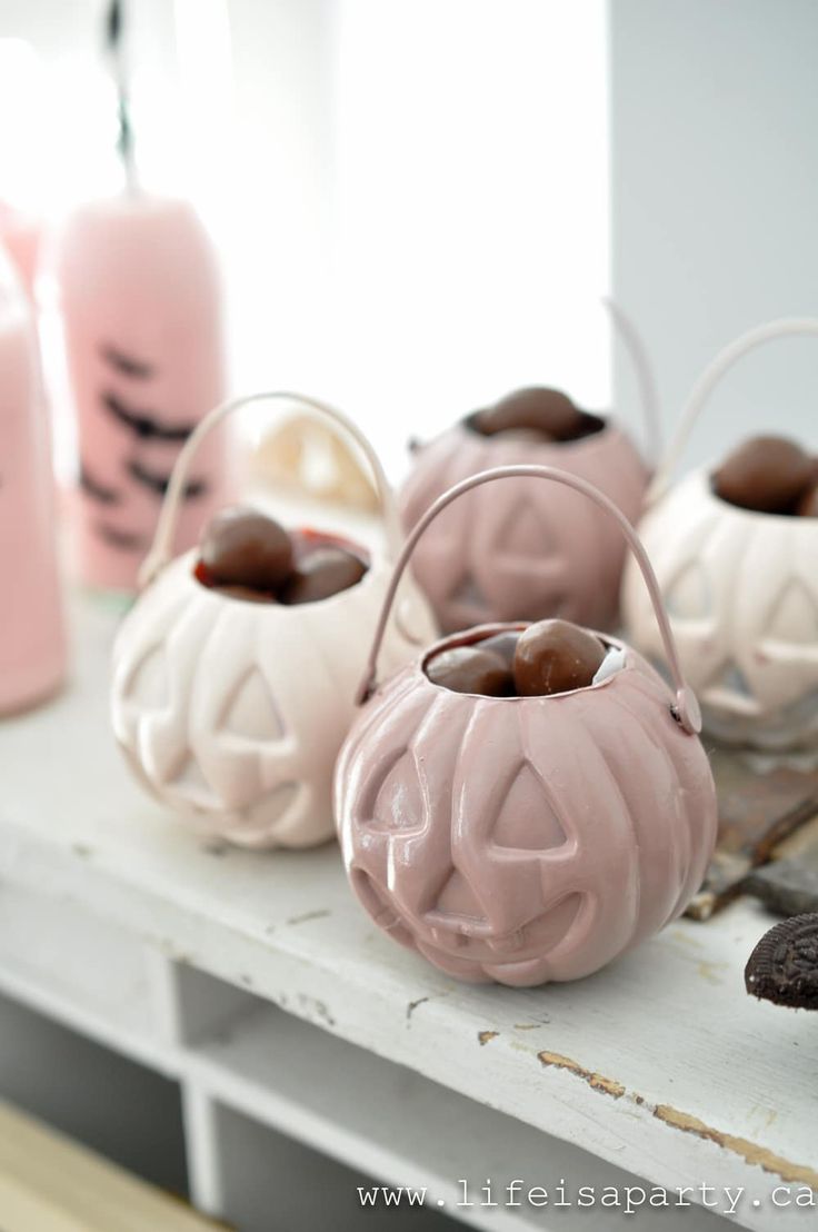 some pink and white pumpkin shaped candles are on a shelf next to other decorative items