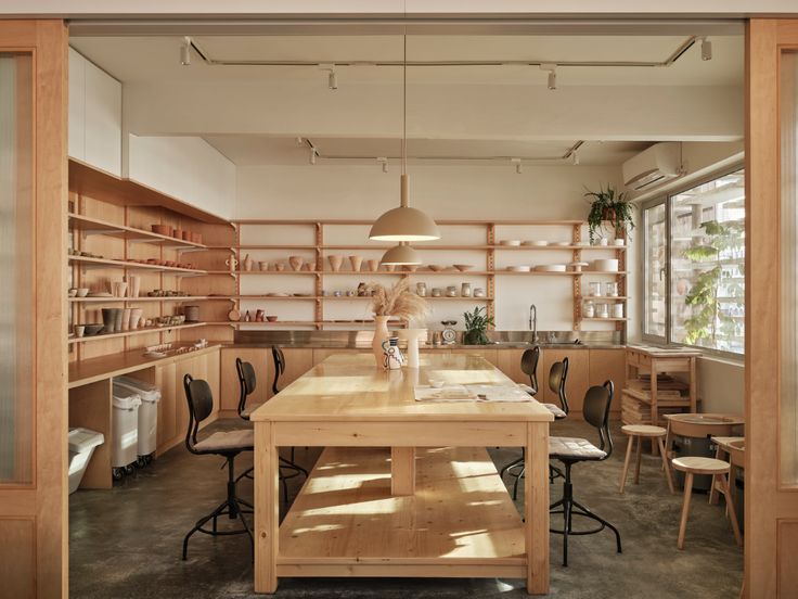 an empty room with wooden tables and chairs in the center, surrounded by shelving