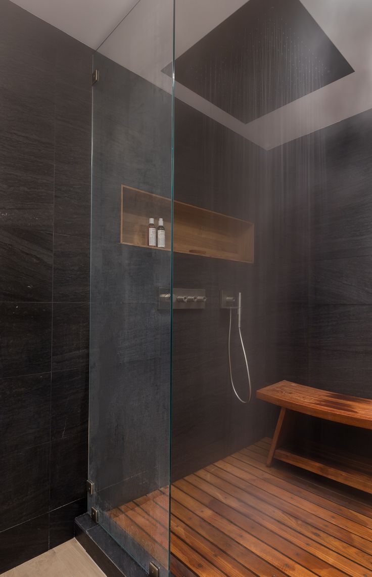 a wooden bench sitting inside of a glass shower