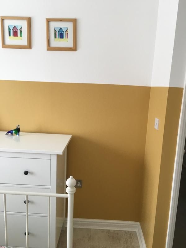 a baby crib in a room with two pictures on the wall and a dresser next to it