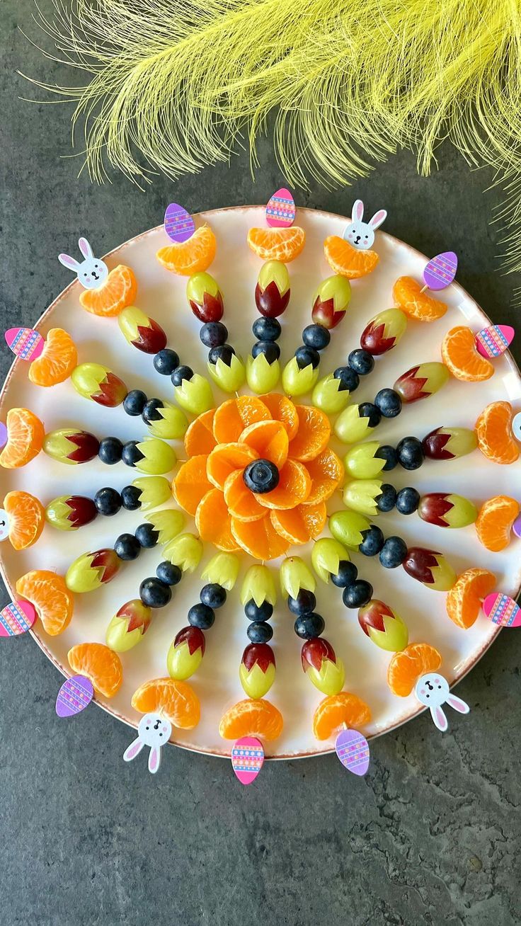 a white plate topped with lots of colorful candies on top of a table next to a yellow feather