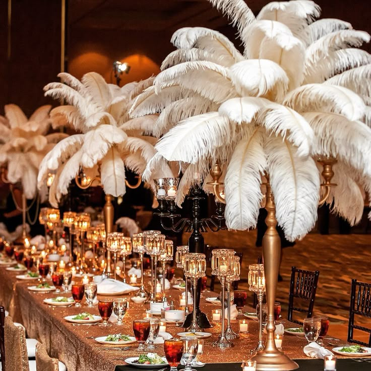 a long table is set with white feathers and candles for an elegant dinnereon party