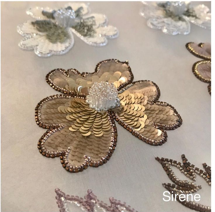 several different types of sequins and flowers on a white tablecloth with silver trim