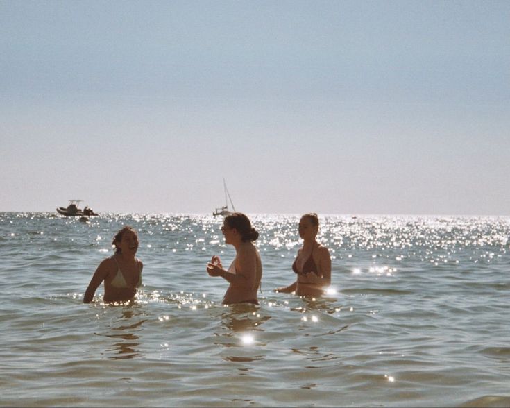 three people are in the water and one is holding a cell phone