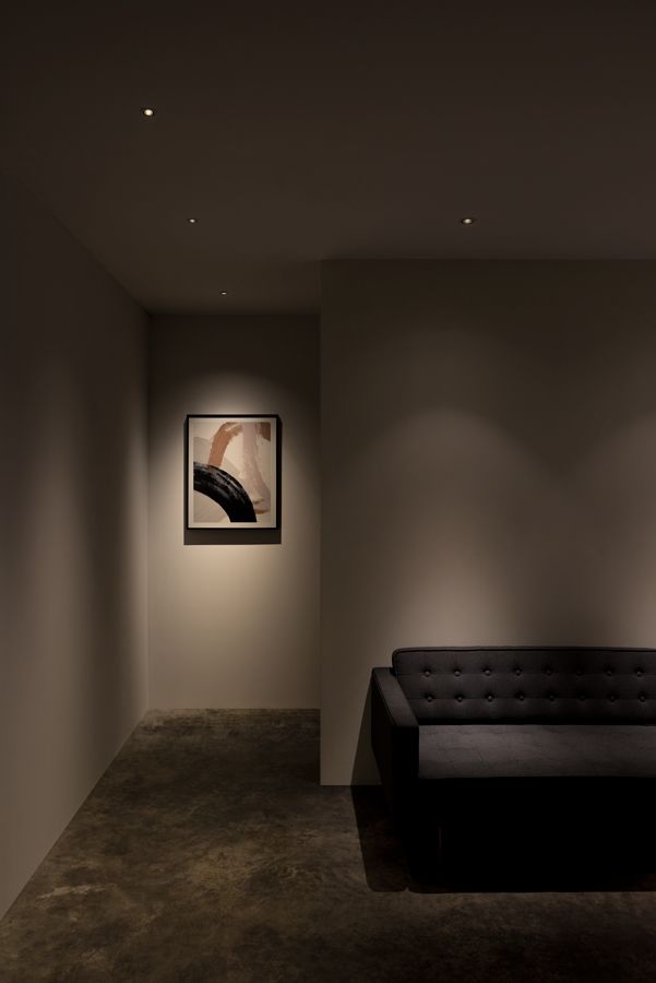 an empty room with a black couch and two paintings on the wall behind it,