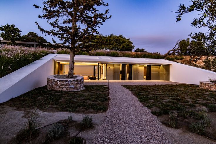 the house is surrounded by trees and grass, with a stone pathway leading to it