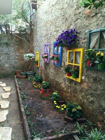 an outdoor area with flowers and plants on the side of the building, along with potted plants