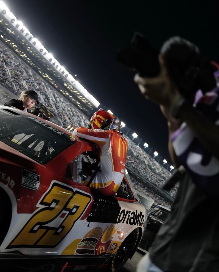 a man standing next to a race car on top of a field