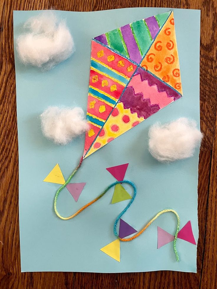 a kite that is on top of a piece of paper with some clouds in the background