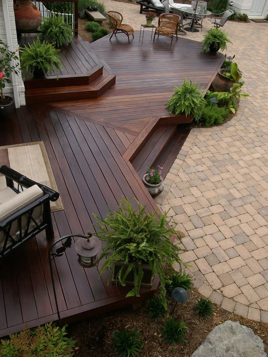 a deck with steps leading up to an outdoor living room and dining area in the background