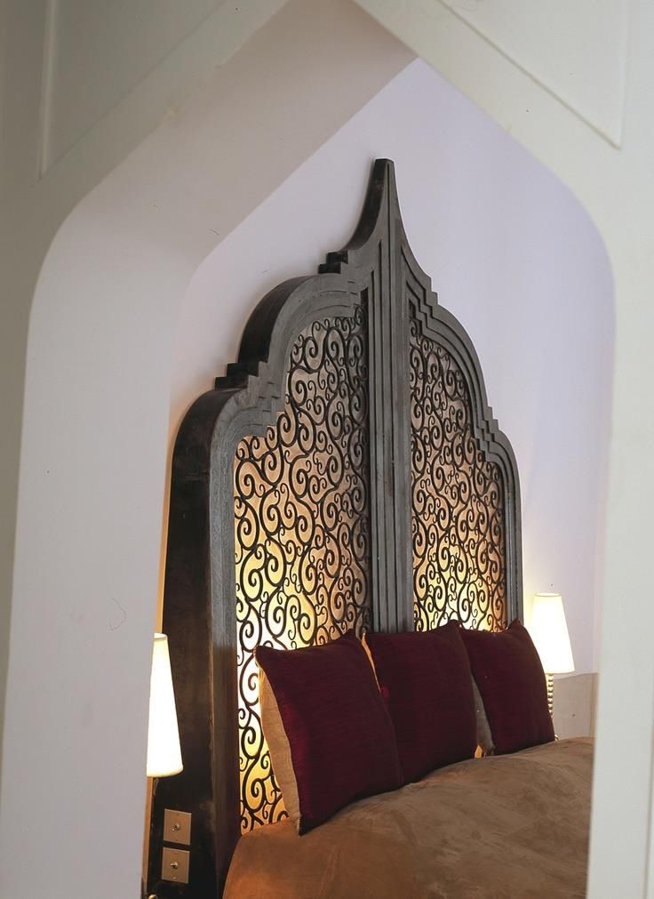 an ornate headboard with red pillows in a bedroom