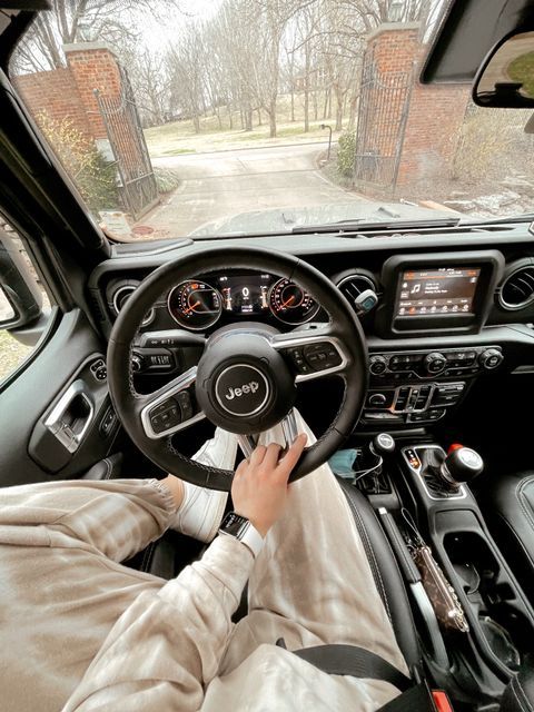 a person driving a car with the steering wheel up and hands on the dash board