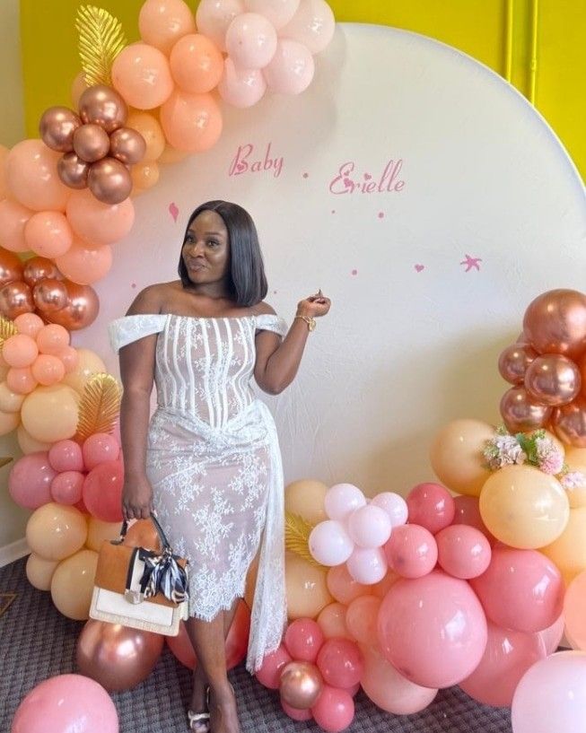 a woman standing in front of balloons with her hand on her hip and pointing to the side