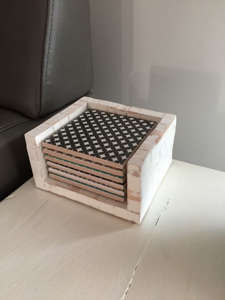 a stack of black and white coasters sitting on top of a wooden table next to a leather chair