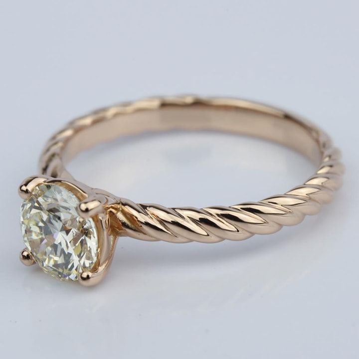 a gold ring with a white diamond in the center and a twisted band around it