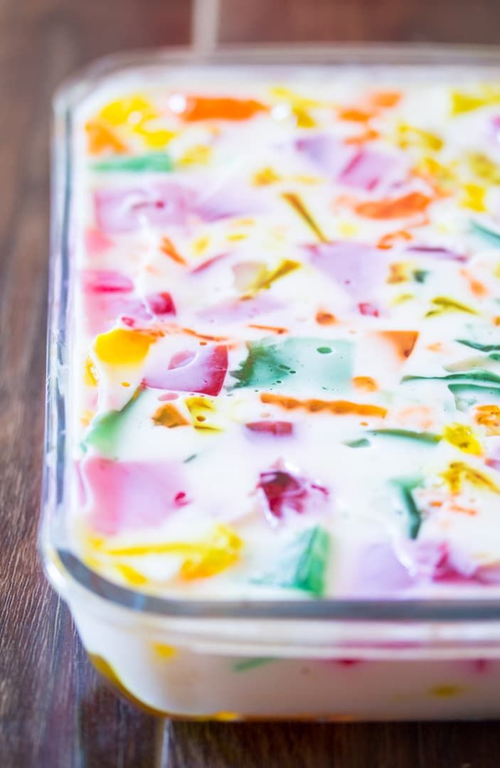 a colorful cake in a glass dish on a wooden table